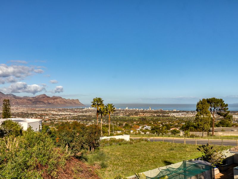 An expansive elevated view overlooking the surrounding landscape, distant mountains, and coastal city skyline under a clear blue sky.