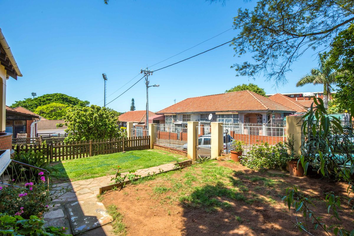 A view of the rear garden area featuring a stone pathway, lawn, and perimeter fencing, providing access to the property's outdoor space.