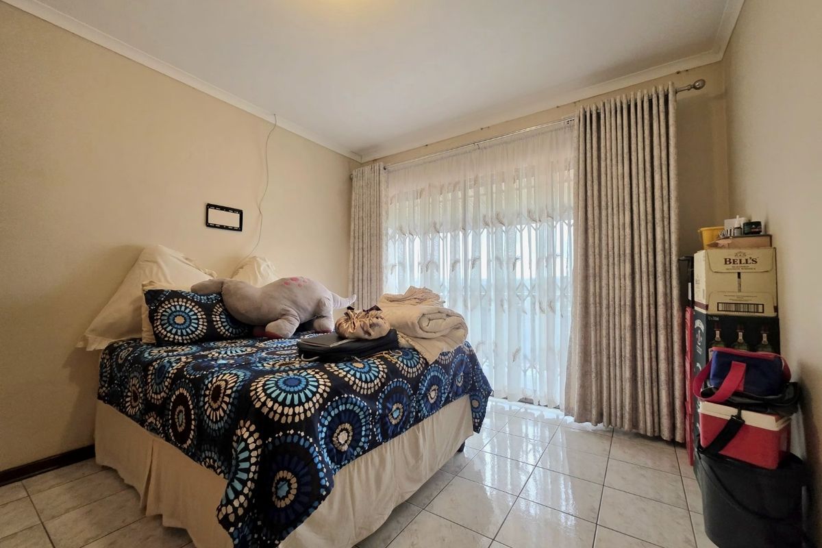 A bedroom featuring tiled flooring, a sliding glass door with security gate, and neutral wall finishes.