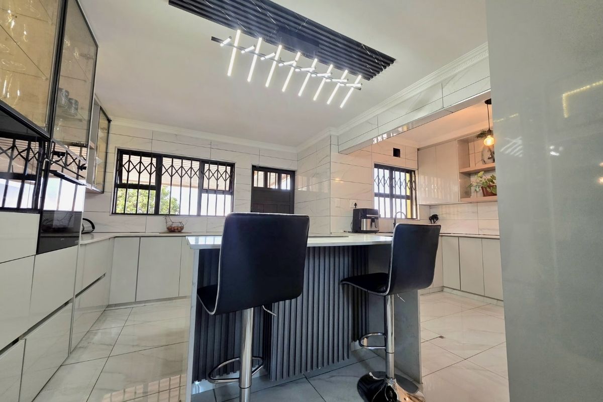 A modern, high-end kitchen featuring a central island, sleek cabinetry, marble-look tiling, and contemporary pendant lighting, offering a clean and sophisticated culinary space.