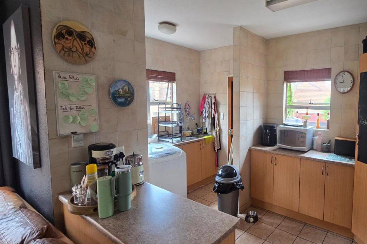 A functional kitchen featuring laminate cabinetry, tiled backsplash, and tiled flooring, offering a practical layout with integrated sink and prep areas.