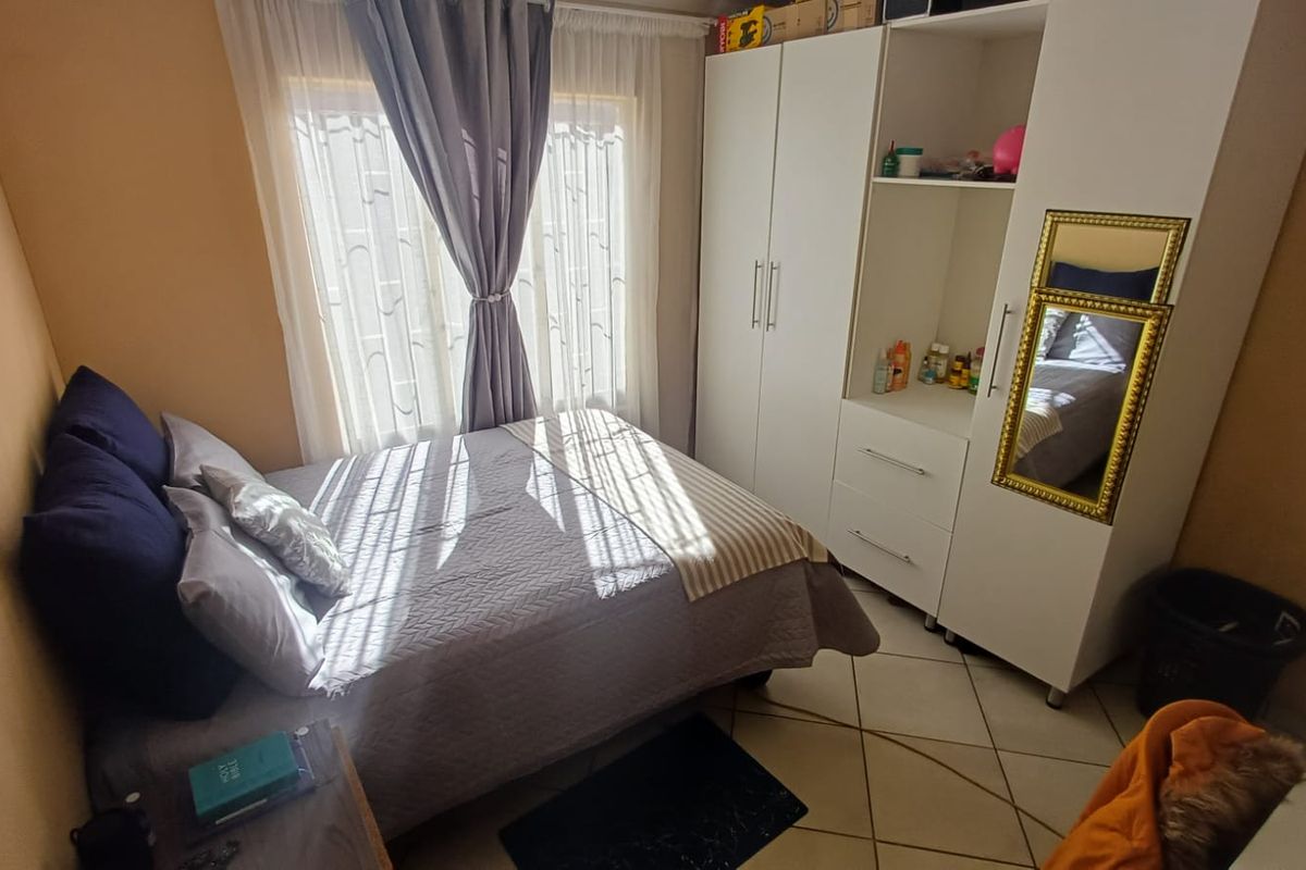 A functional bedroom featuring tiled flooring and a built-in wardrobe, offering a practical layout with natural light from the window.