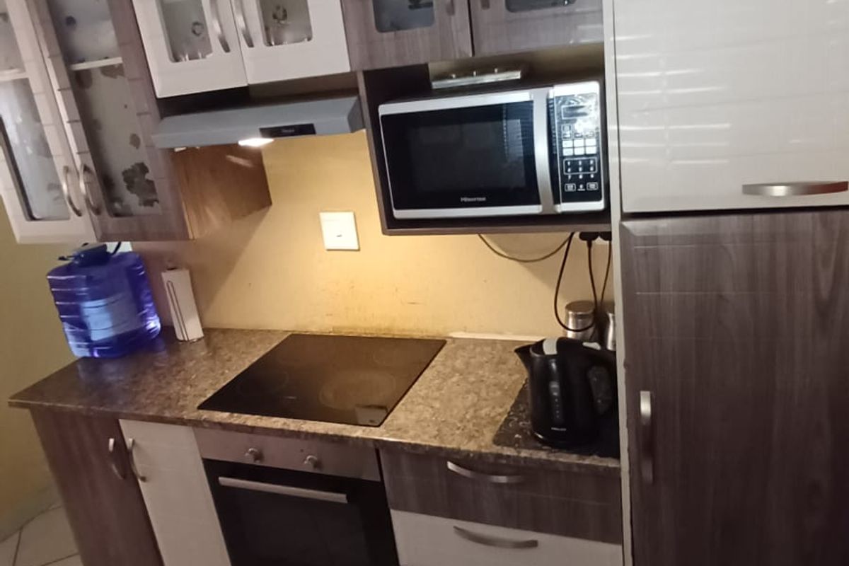 A functional kitchen featuring two-tone cabinetry, integrated appliances including an oven and hob, and tiled flooring.