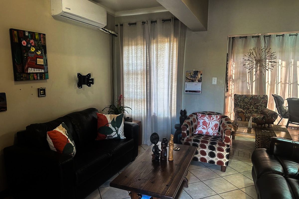 A comfortable living room featuring tiled flooring and a wall-mounted split-system air conditioning unit.