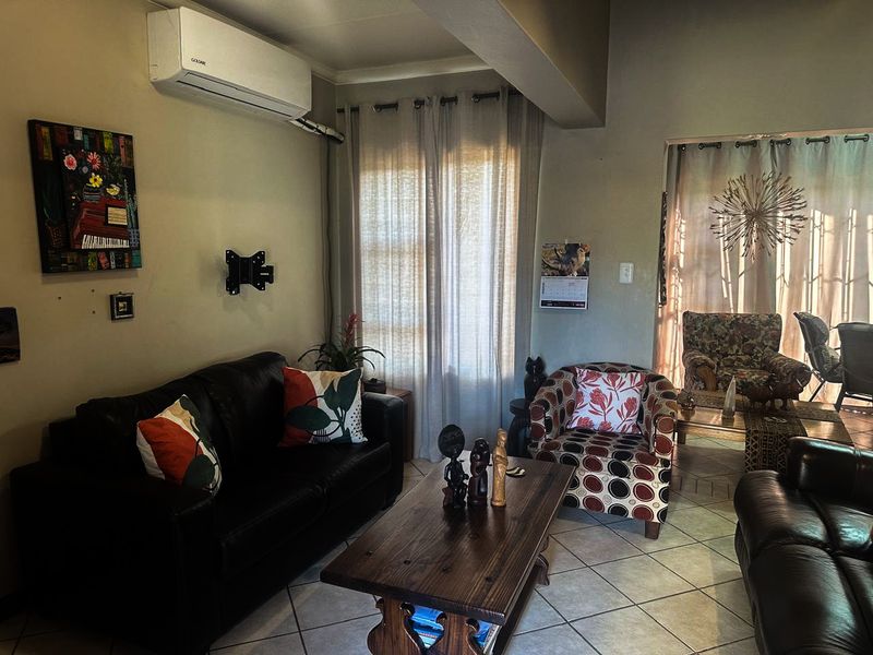 A comfortable living room featuring tiled flooring and a wall-mounted split-system air conditioning unit.