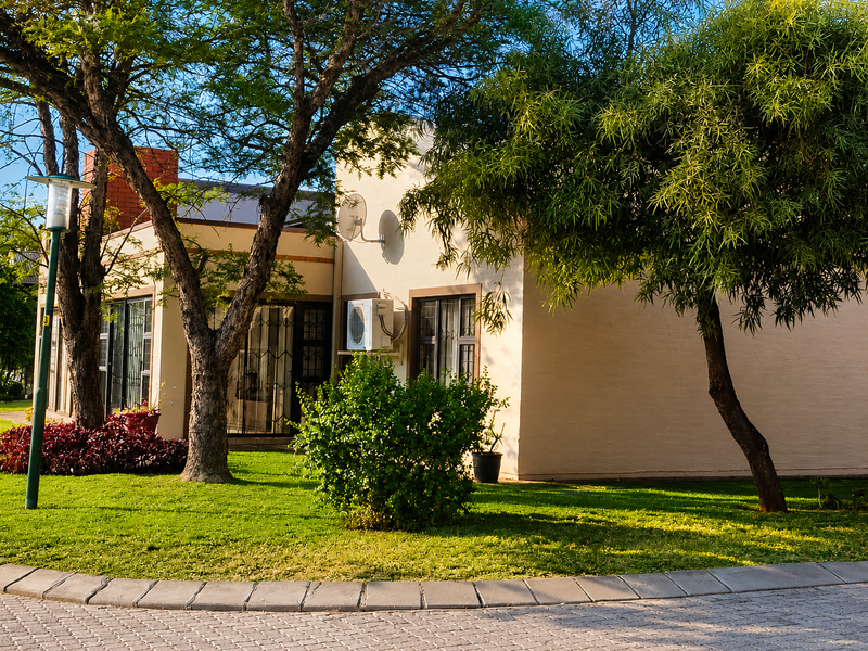 Front exterior view of the property featuring a well-maintained garden, paved driveway, and established trees.