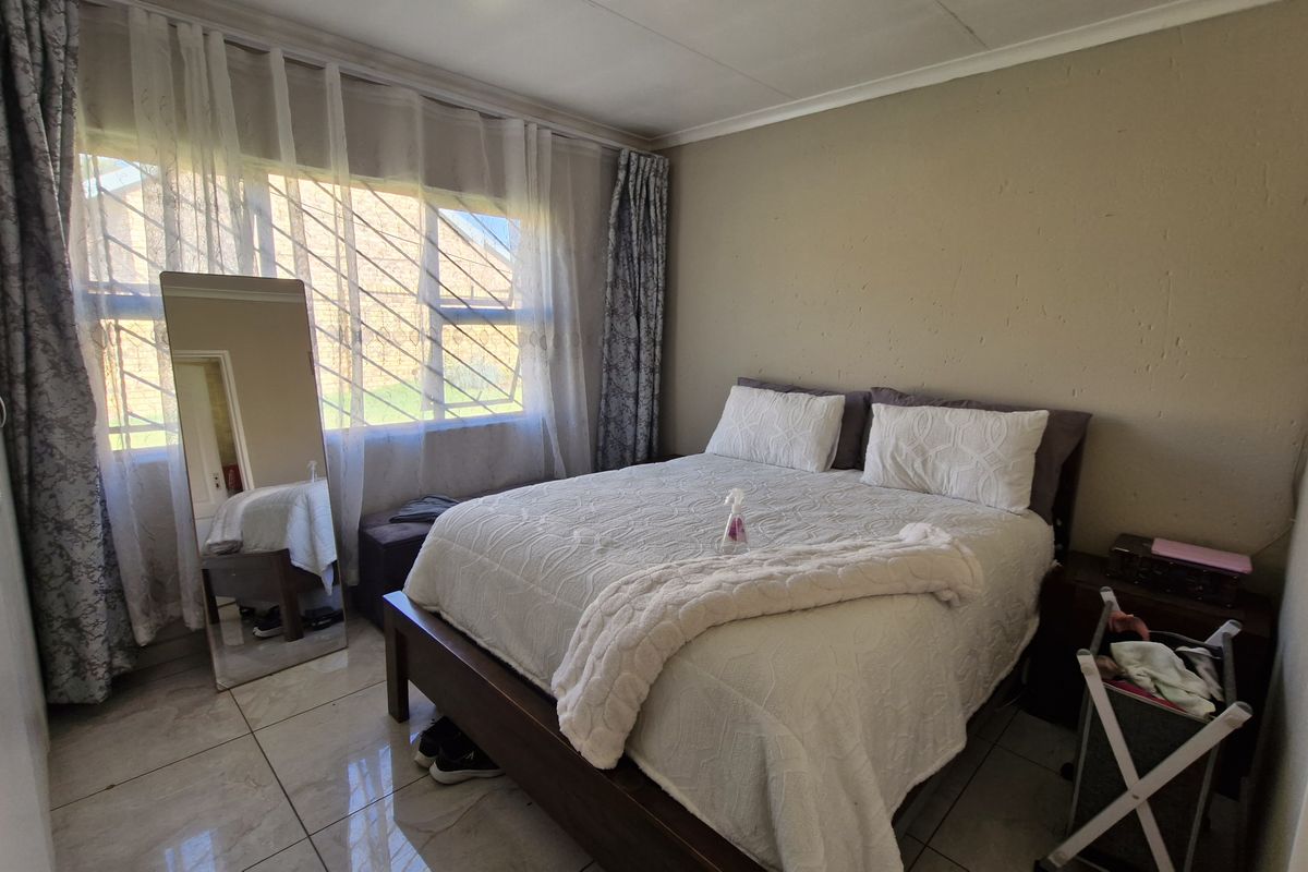 A bedroom featuring tiled flooring, built-in wardrobe storage, and security bars on the window.
