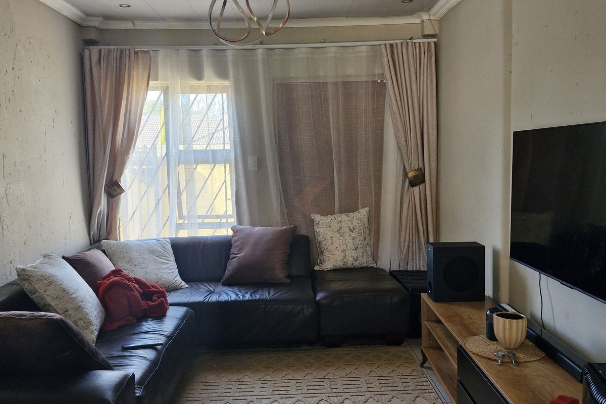 A living room featuring recessed lighting and security bars on the windows, currently showing signs of wear on the wall finishes.