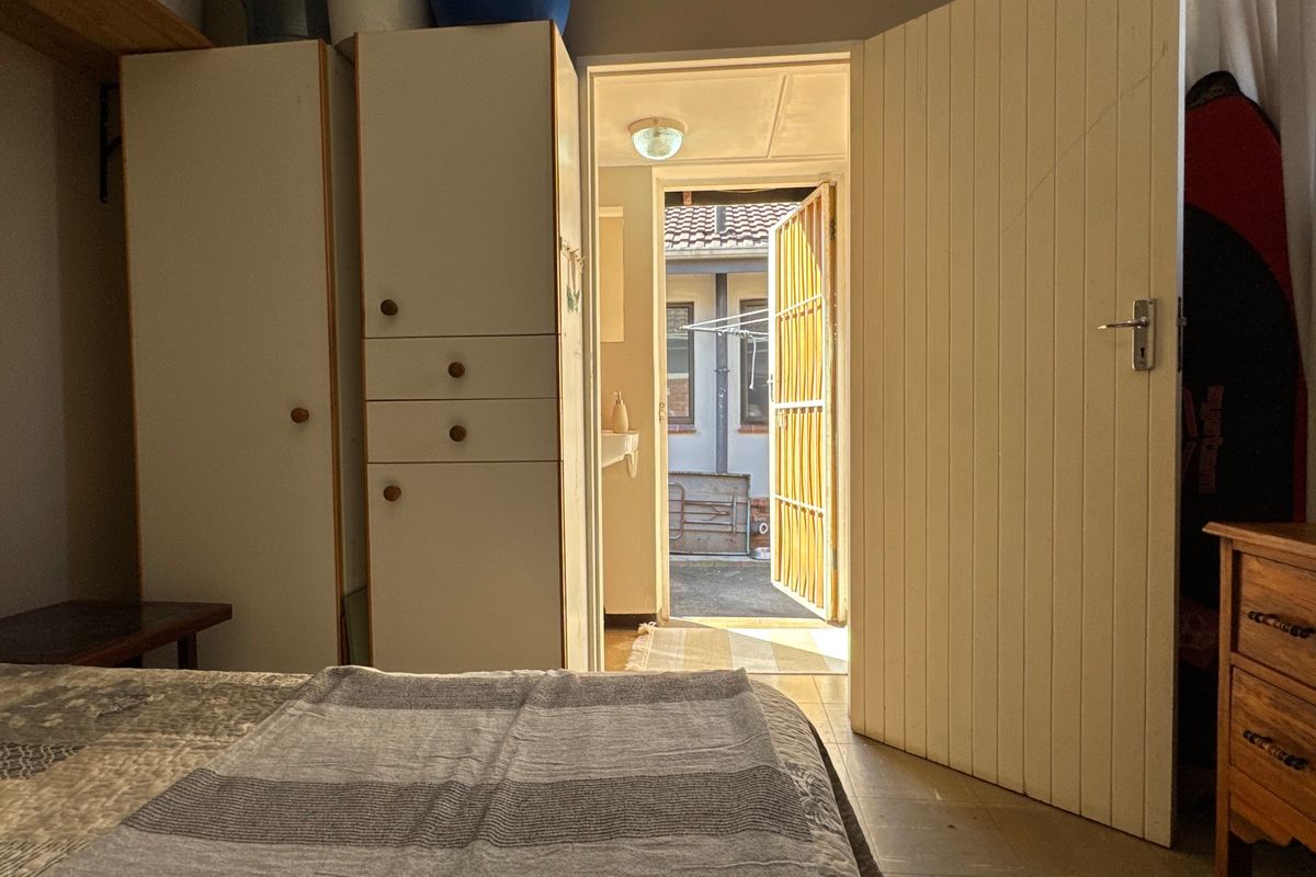 Bedroom featuring built-in cupboards and direct access to an exterior courtyard area through a timber door.