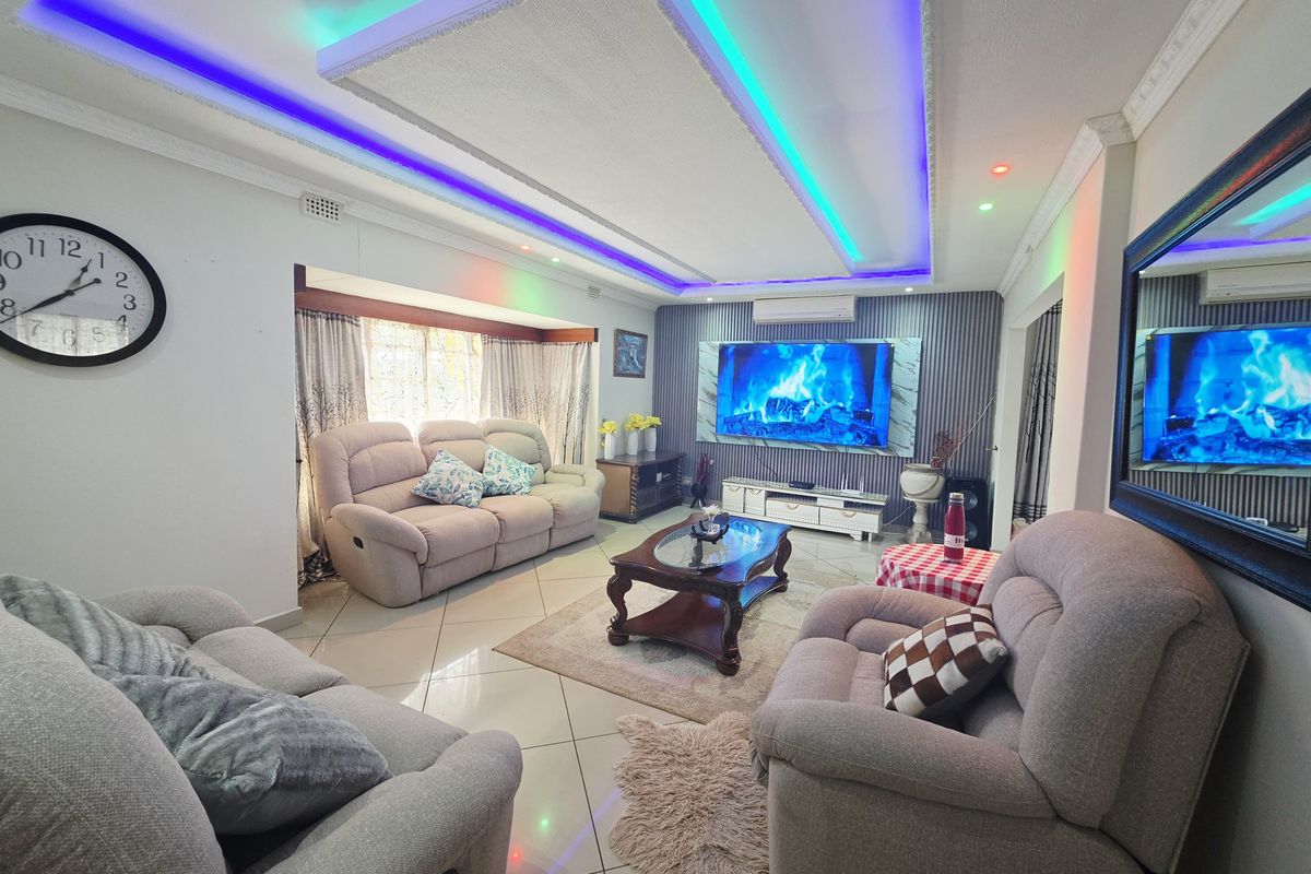 A well-maintained living room featuring a modern recessed ceiling with integrated LED lighting, tiled floors, and a split-system air conditioner.