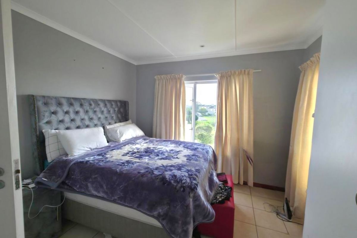 A bedroom featuring tiled flooring and natural light from a window with curtain tracks.