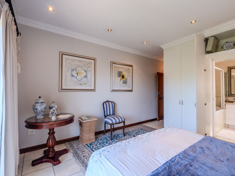 Spacious bedroom featuring built-in cupboards, recessed downlights, tiled flooring, and direct access to an en-suite bathroom.