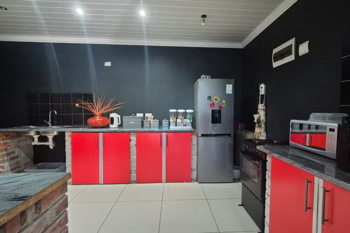 Kitchen featuring red cabinetry, exposed brick base detailing, tiled backsplash, and tiled flooring with a tongue and groove ceiling.