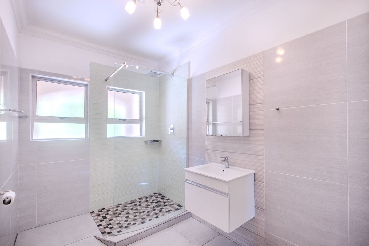 Modern bathroom featuring a walk-in shower with glass screen, wall-mounted vanity with basin, and neutral tiled finishes throughout.