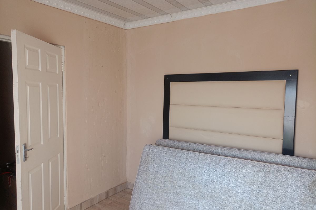 A bedroom featuring tiled flooring, a panelled ceiling with coving, and a neutral wall finish, currently vacant and ready for staging.
