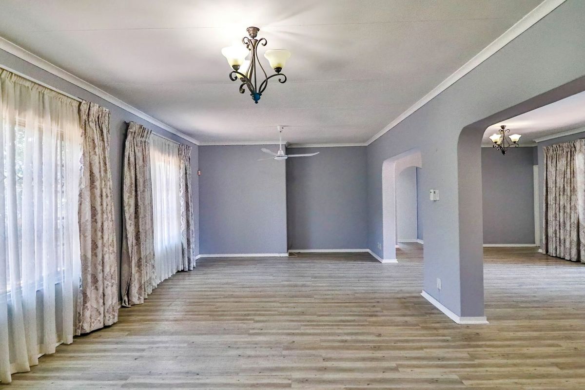 Spacious, light-filled living area featuring modern laminate flooring, neutral wall tones, and an open-plan layout with elegant archways.
