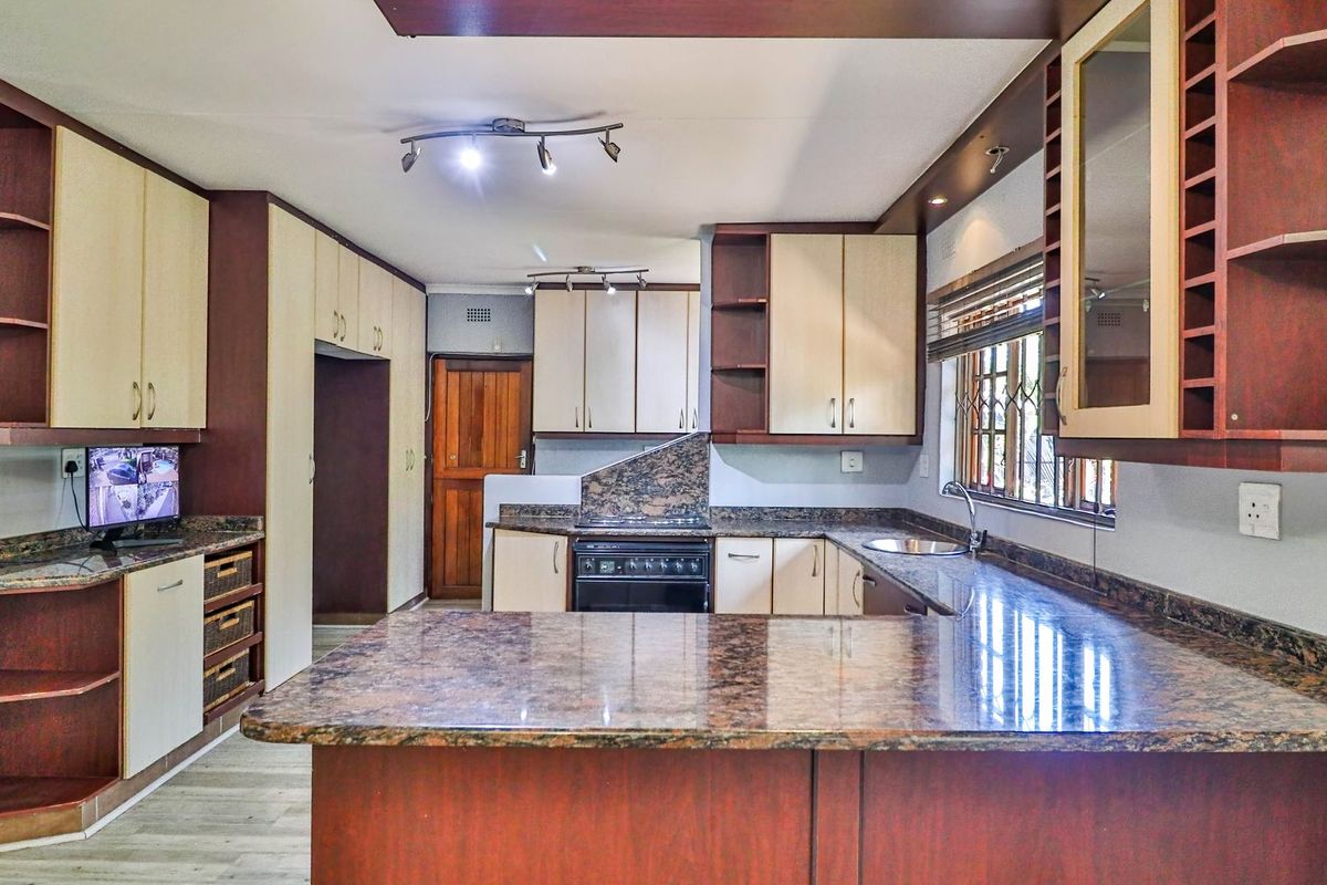 A functional kitchen featuring granite countertops, ample built-in cabinetry, and a freestanding stove, offering a practical layout with potential for modern updates.