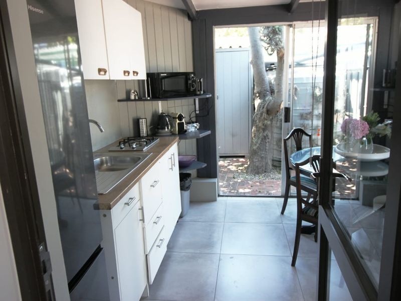 Compact kitchen featuring white cabinetry, gas hob, stainless steel sink, and direct access to an outdoor patio area through sliding glass doors.