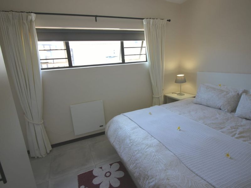 A bedroom featuring tiled flooring, a horizontal sliding window, and a wall-mounted electric heater.