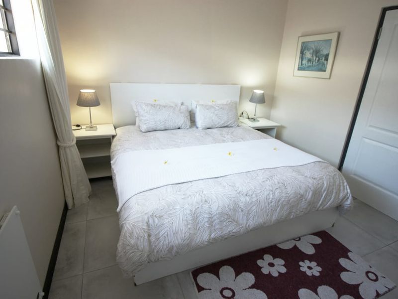 A well-maintained bedroom featuring neutral wall tones, tiled flooring, and a wall-mounted panel heater.