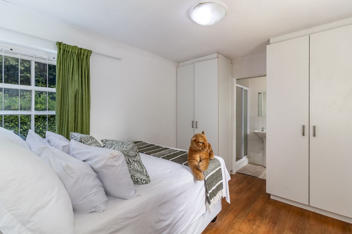 A bedroom featuring built-in wardrobes, laminate flooring, and an en-suite bathroom with a shower.