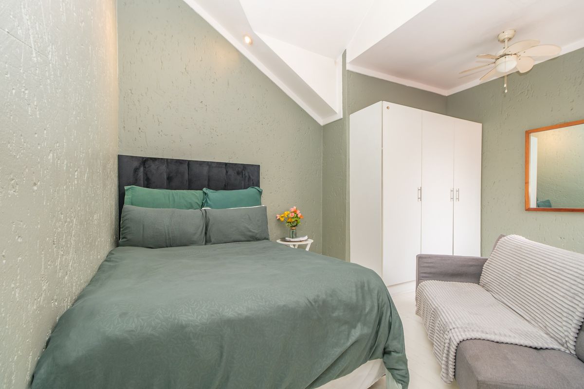A well-lit bedroom featuring a built-in wardrobe, ceiling fan, and unique textured wall finishes, providing a comfortable and functional living space.