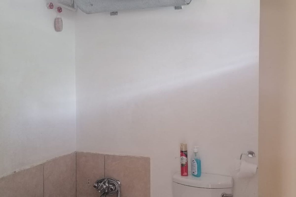 A functional bathroom featuring a bathtub, toilet, and wall-mounted electric water heater. The space requires cosmetic updates to improve its overall condition and aesthetic appeal.