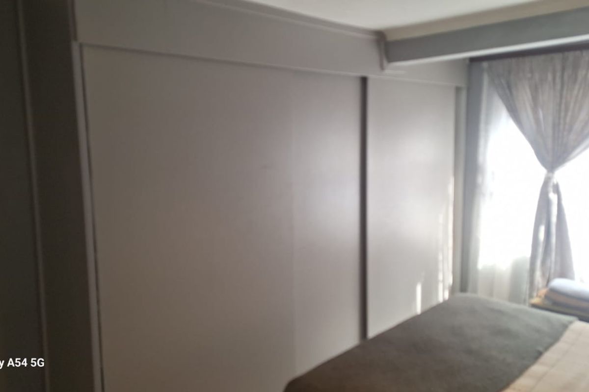 A bedroom featuring a large built-in sliding door wardrobe and natural light from the window.