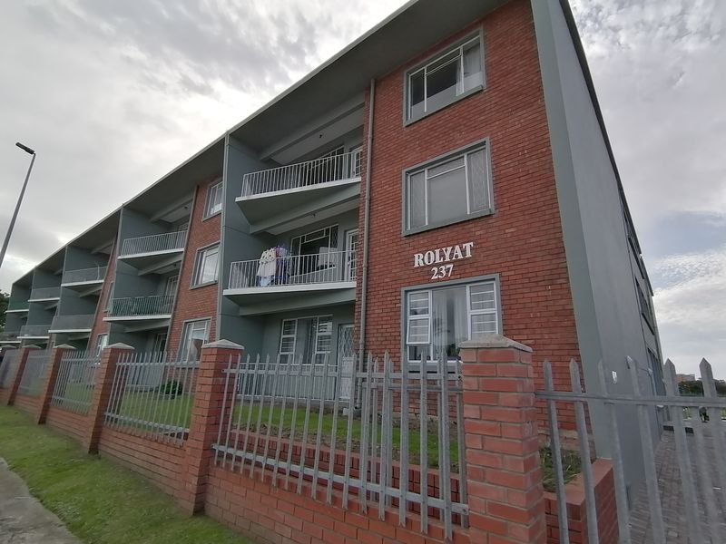 Exterior view of the Rolyat 237 apartment building, featuring a brick and painted facade with secure metal perimeter fencing and private balconies.