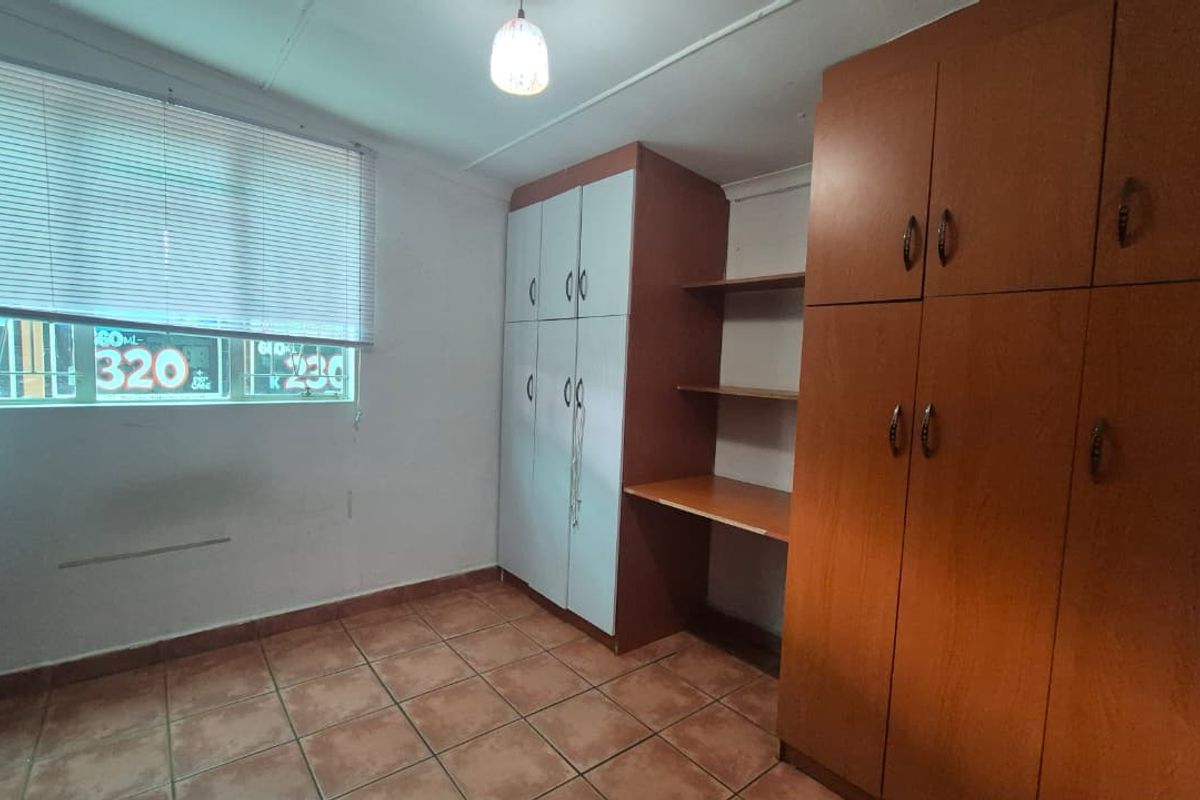 A functional bedroom featuring tiled flooring and extensive built-in cabinetry with integrated shelving and storage space.