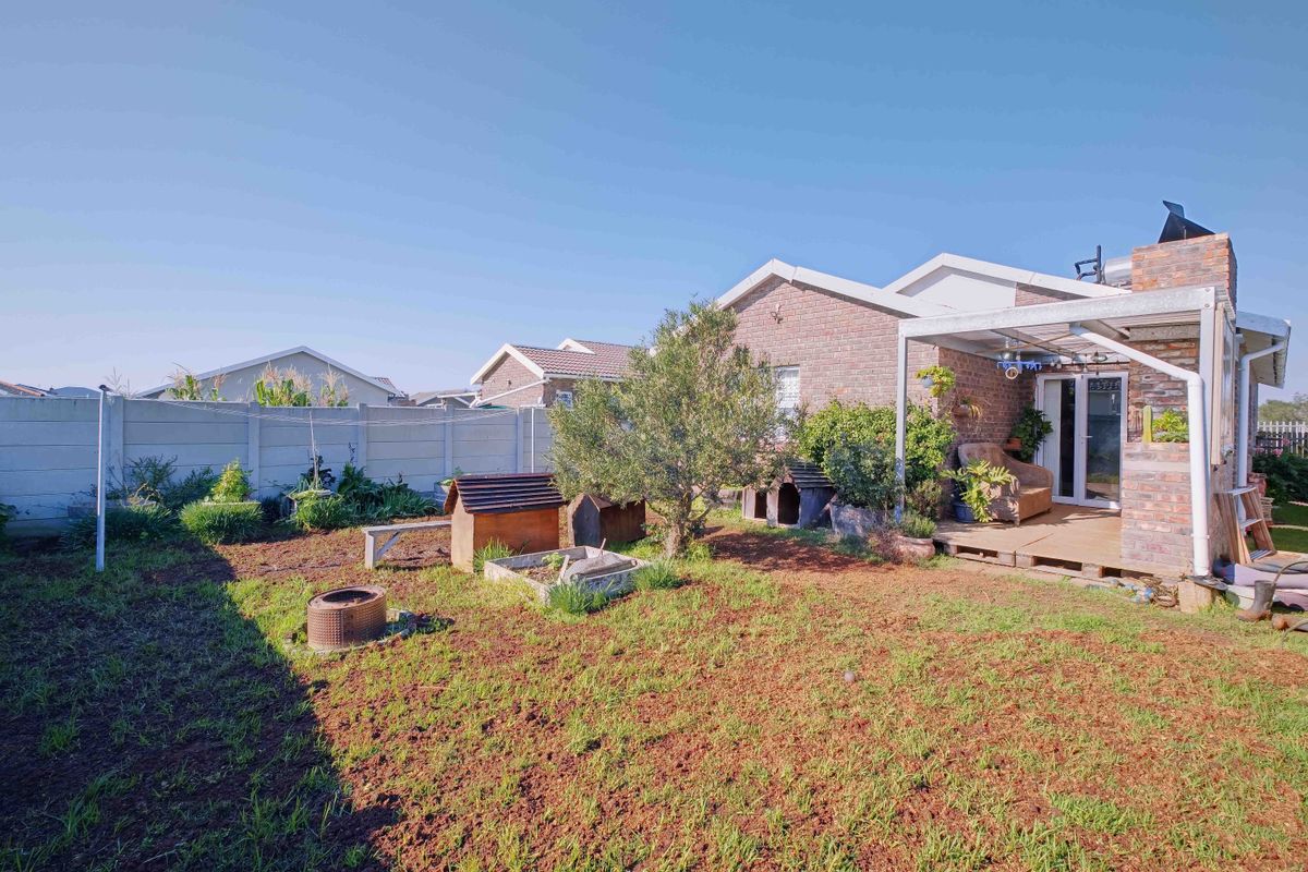 Rear view of the property featuring a brick facade, a covered patio area, and a garden with a precast concrete boundary wall.