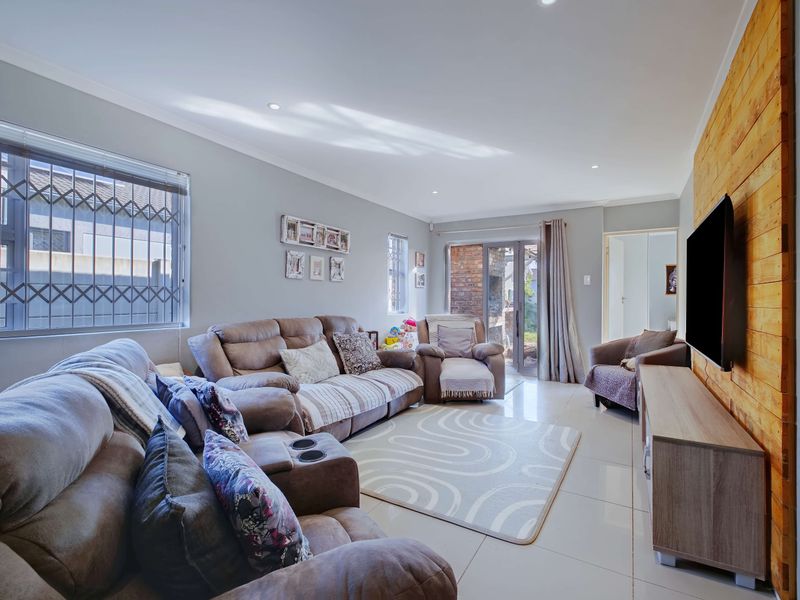 A bright living room featuring tiled floors, recessed lighting, a timber feature wall, and direct access to the outdoor area through sliding glass doors.