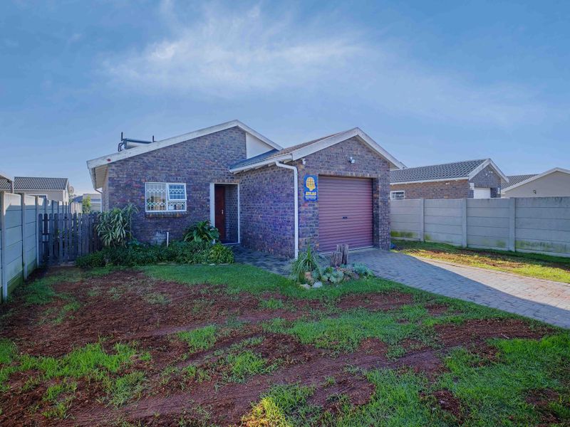 Front view of a face brick house featuring a single garage, paved driveway, and enclosed yard with precast boundary walls.
