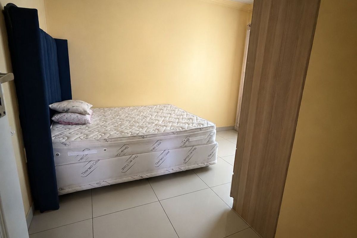 A bedroom featuring tiled flooring, a tongue and groove ceiling, and a built-in wardrobe.