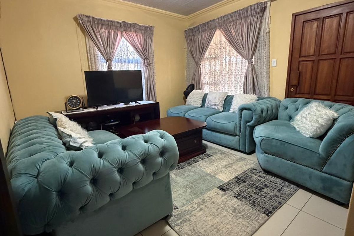A living room featuring tiled flooring, a timber panelled ceiling, and a solid timber door, providing a functional and traditional living space.