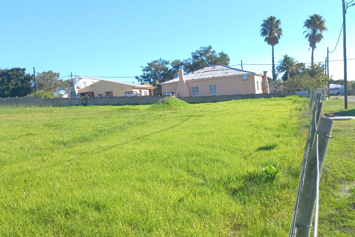 A vacant residential plot of land featuring grassed terrain and perimeter fencing, situated in a developed neighborhood setting.