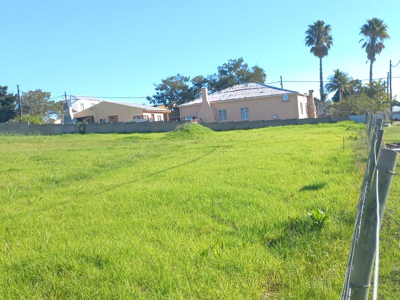 A vacant residential plot of land featuring grassed terrain and perimeter fencing, situated in a developed neighborhood setting.