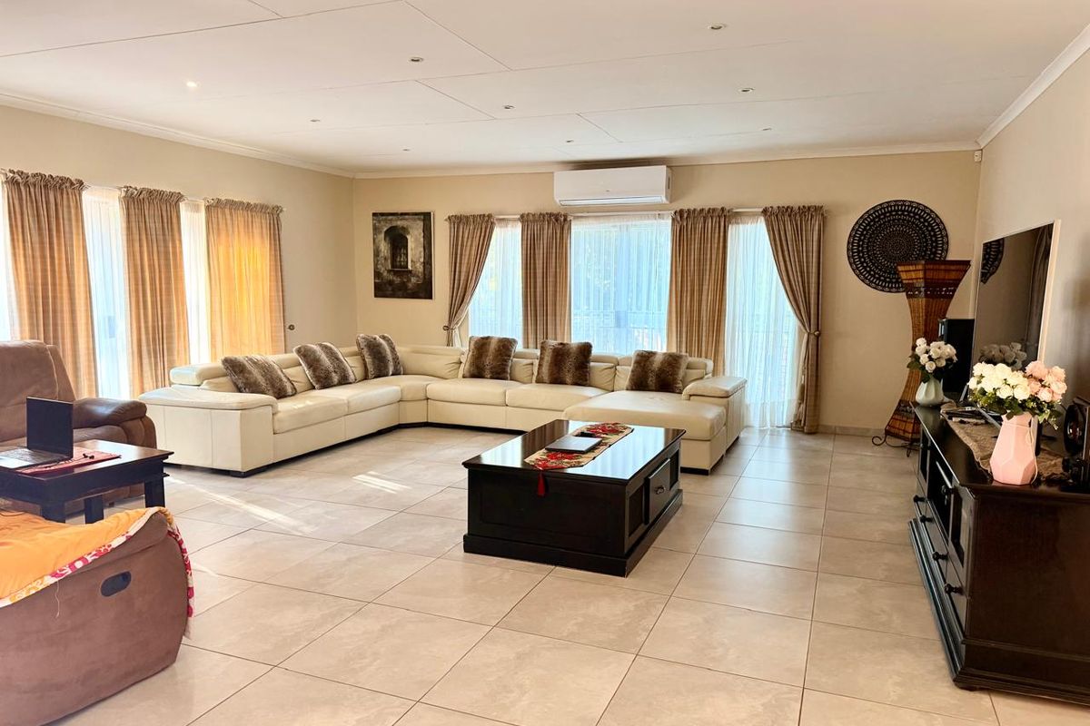 Spacious living room featuring large format floor tiles, recessed lighting, and a wall-mounted split-system air conditioning unit.