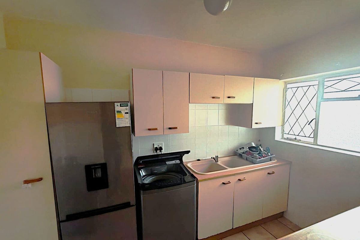 A functional kitchen featuring built-in cabinetry, a double basin sink, tiled backsplash, and tiled flooring, offering a practical layout for daily use.