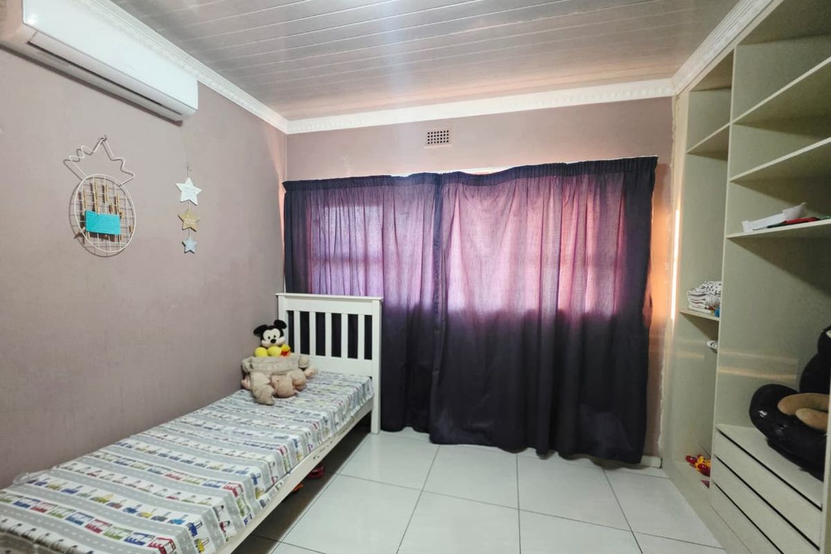 A bedroom featuring tiled flooring, a built-in shelving unit, and a split-system air conditioner.