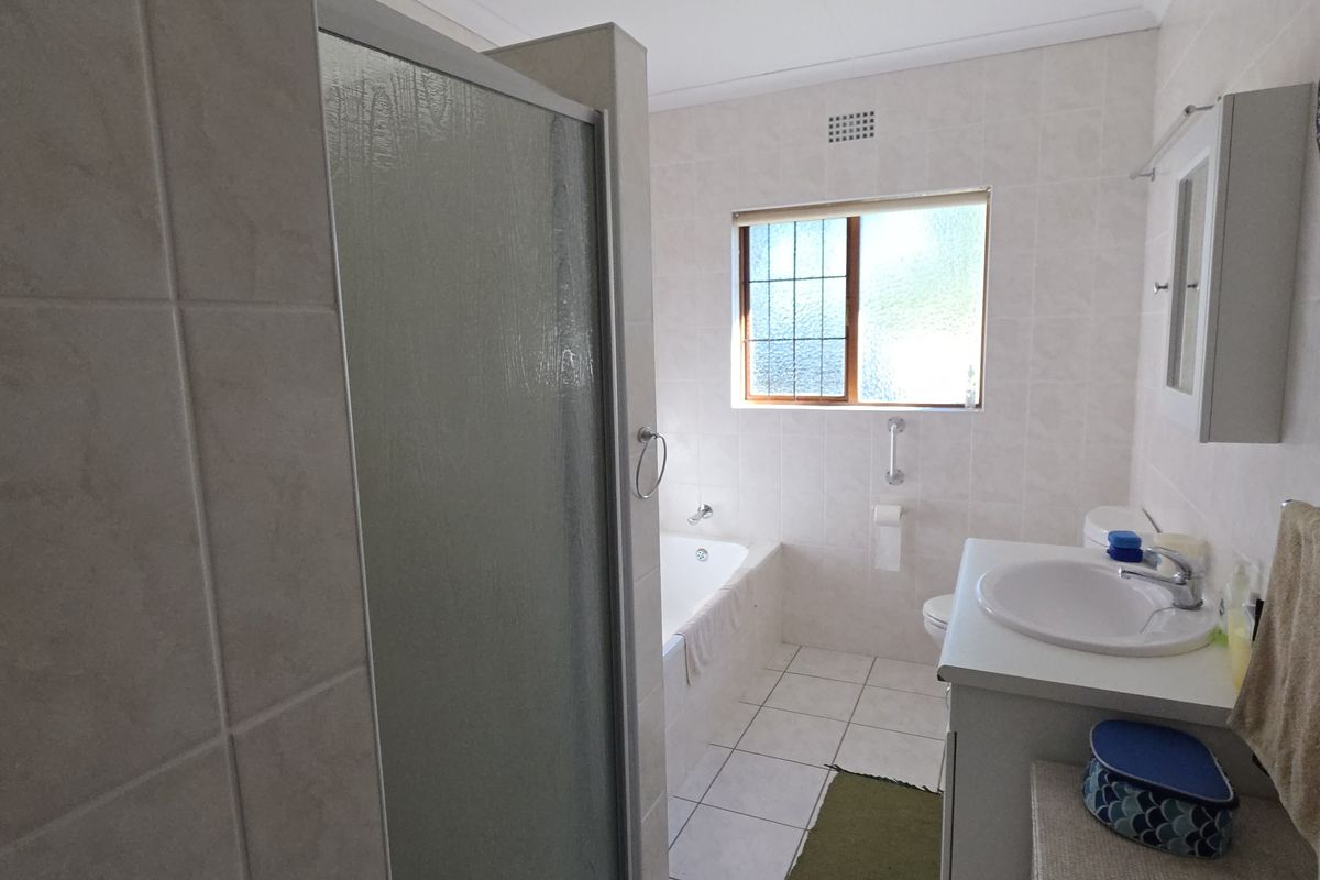 A functional bathroom featuring a built-in bathtub, a separate shower enclosure, and a vanity basin with tiled walls and flooring.