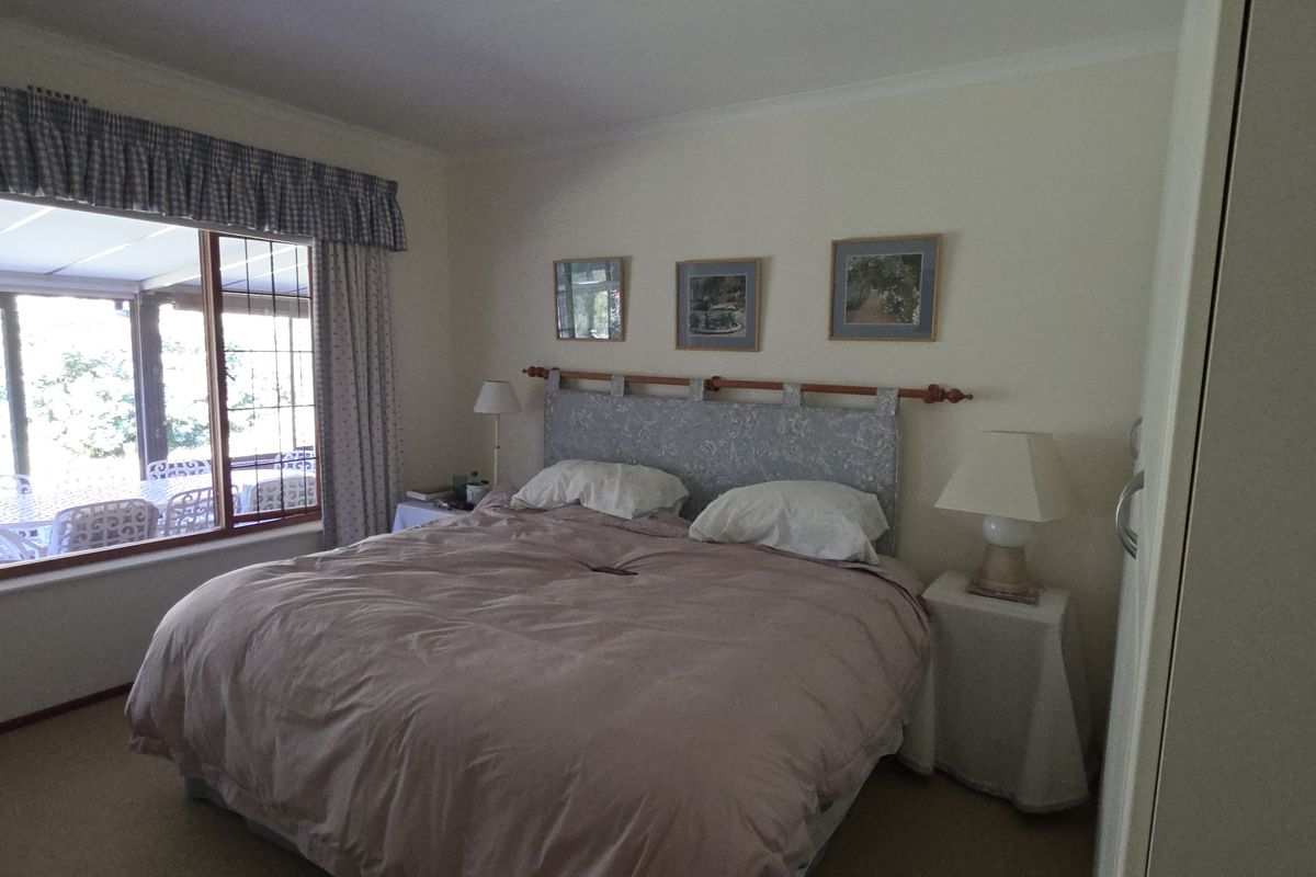 A comfortable bedroom featuring large windows with views of the patio, neutral carpeting, and built-in wardrobe storage.