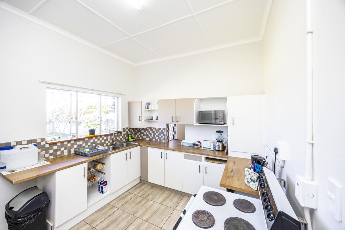 A functional kitchen featuring white cabinetry, wood-look laminate countertops, a tiled backsplash, and a double sink with a window view.