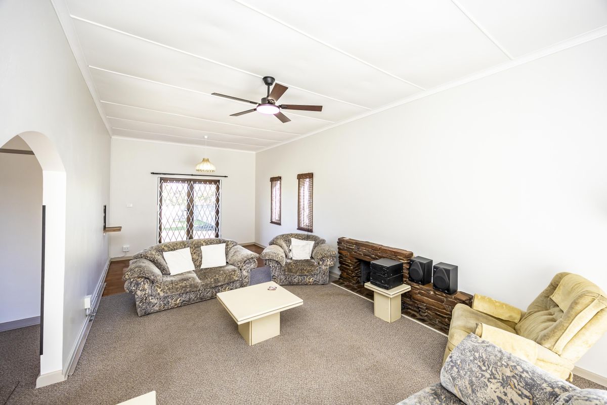 A spacious living room featuring a stone fireplace, ceiling fan, and sliding glass door access to the exterior.