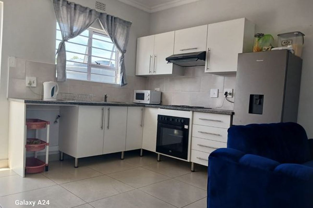 A functional kitchen featuring white built-in cabinetry, a built-in oven with extractor fan, tiled backsplash, and neutral floor tiles.