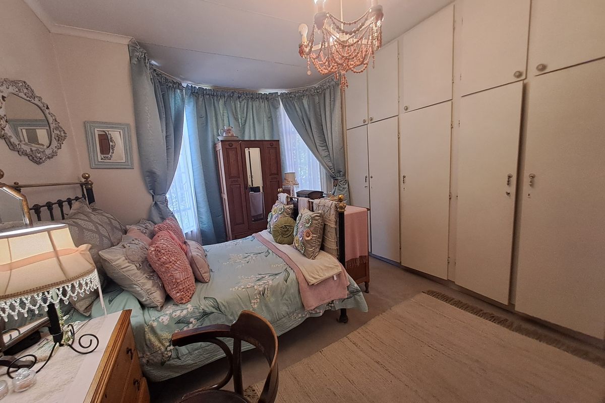 A spacious bedroom featuring extensive floor-to-ceiling built-in cupboards, a classic bay window, and traditional ceiling detailing.