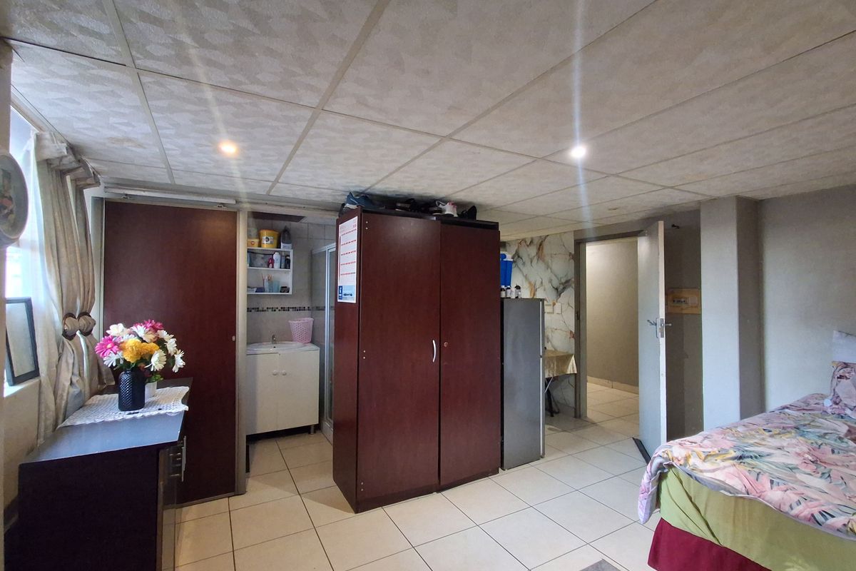 A bedroom featuring tiled flooring, a drop ceiling with recessed lighting, and a small built-in vanity area.