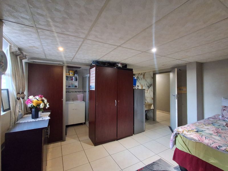 A bedroom featuring tiled flooring, a drop ceiling with recessed lighting, and a small built-in vanity area.