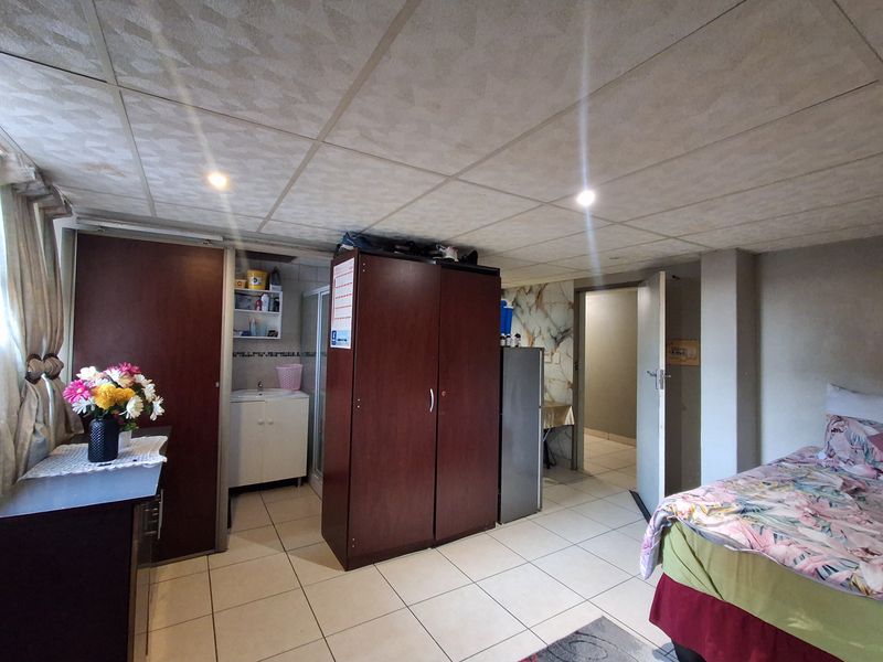 A bedroom featuring tiled flooring, a drop ceiling with recessed lighting, and an integrated vanity area with built-in storage.