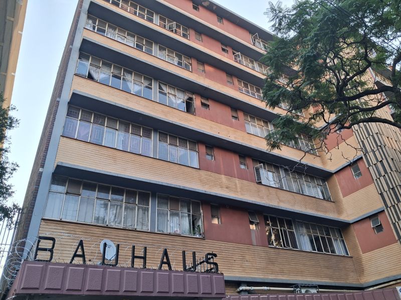 Low-angle view of the Bauhaus apartment building facade, featuring multi-story brickwork and classic metal-framed windows.